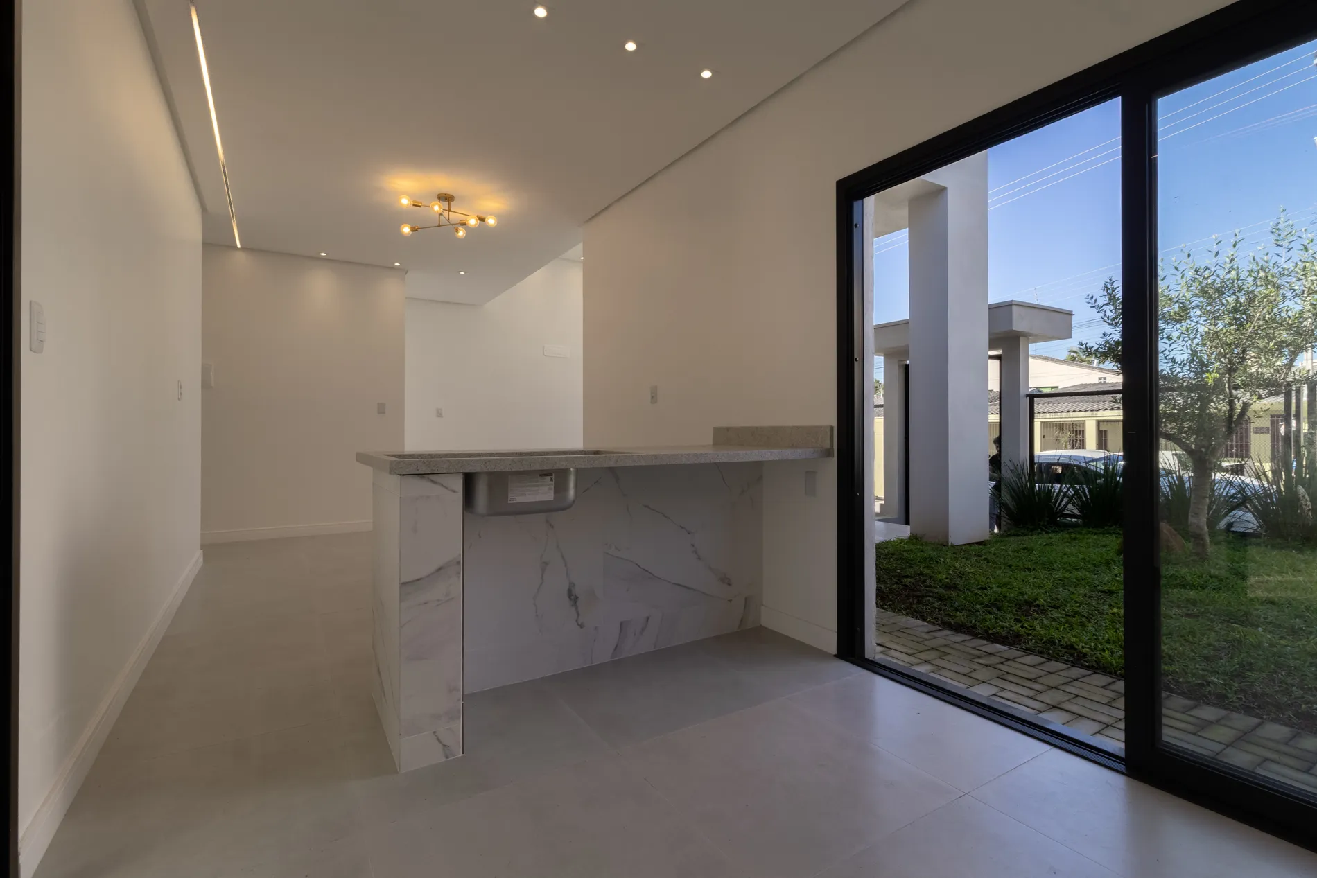 Cozinha com bancada de mármore e porta de vidro para o jardim