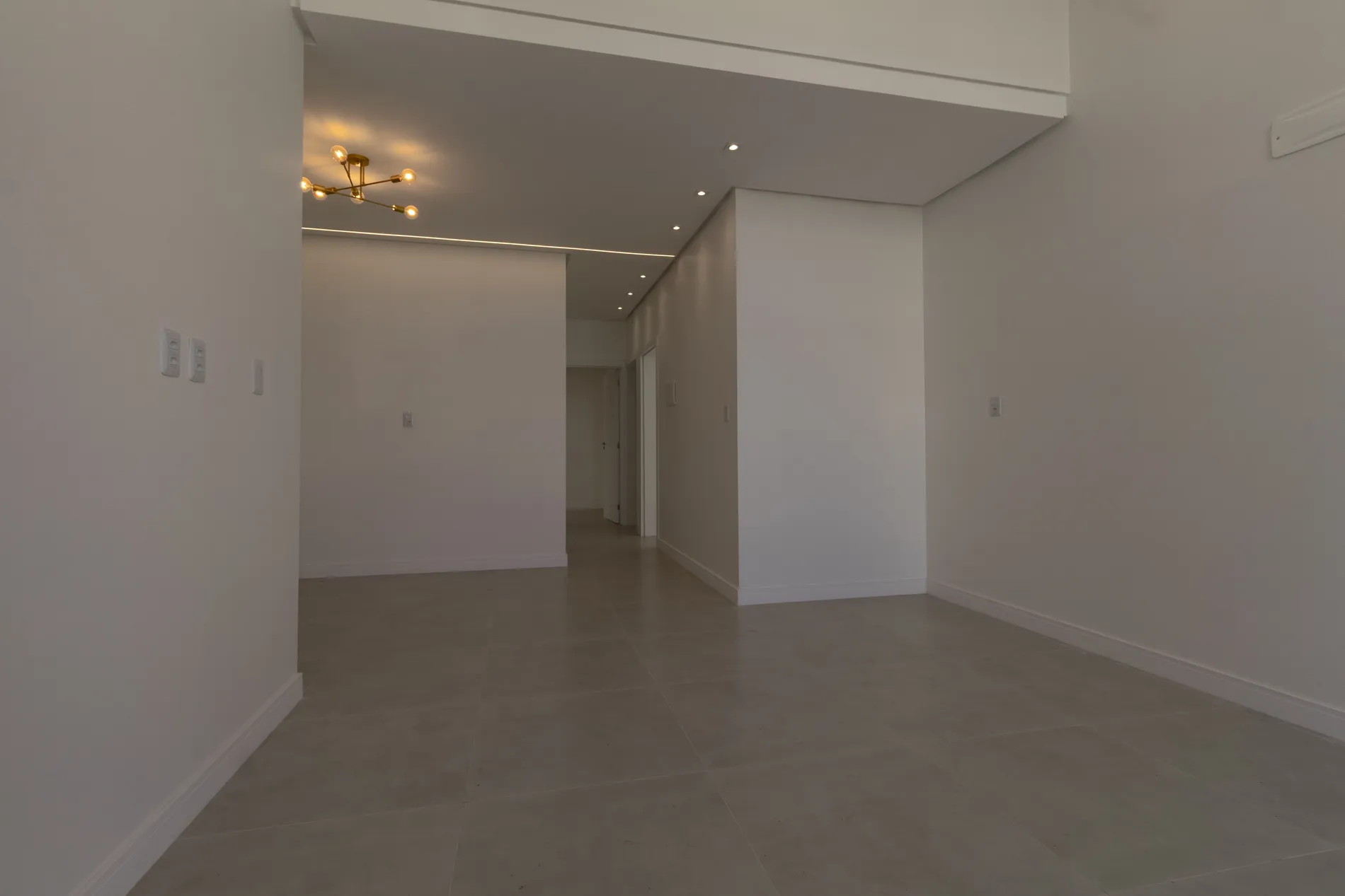 Ambiente amplo com lustre e circulação para os quartos